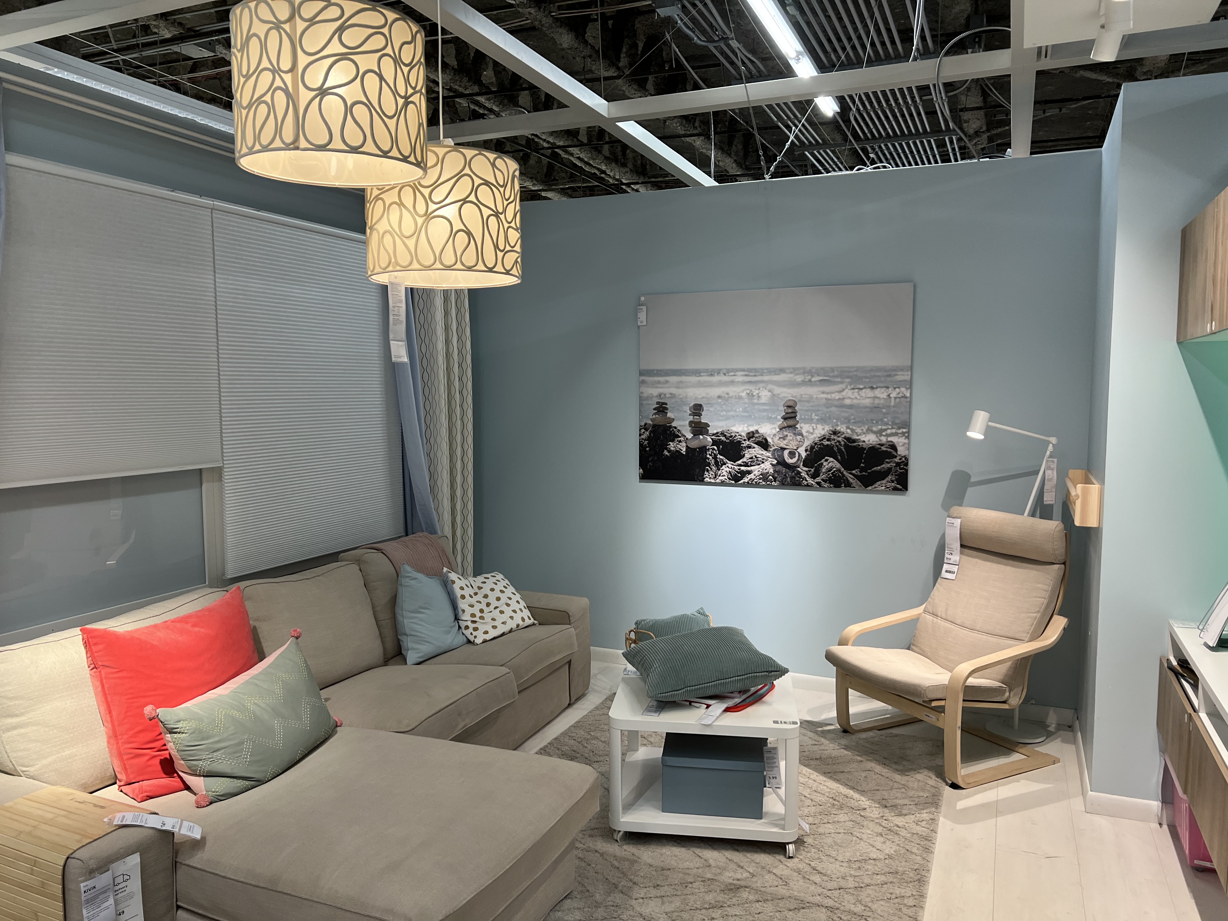 Staged room at IKEA with hanging light fixtures, a couch, chairs, and a painting on the wall