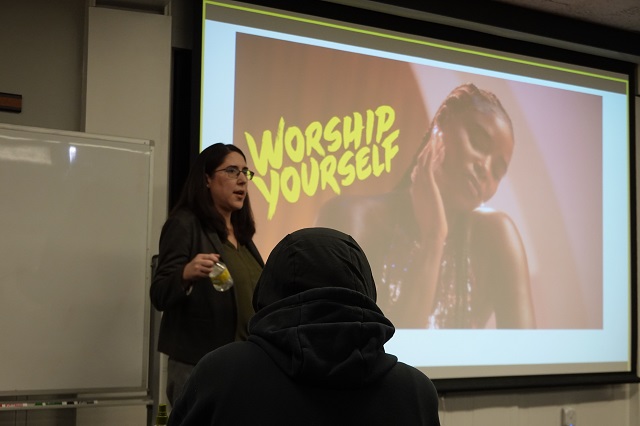 Guest speaker stands in front of presentation slide. 