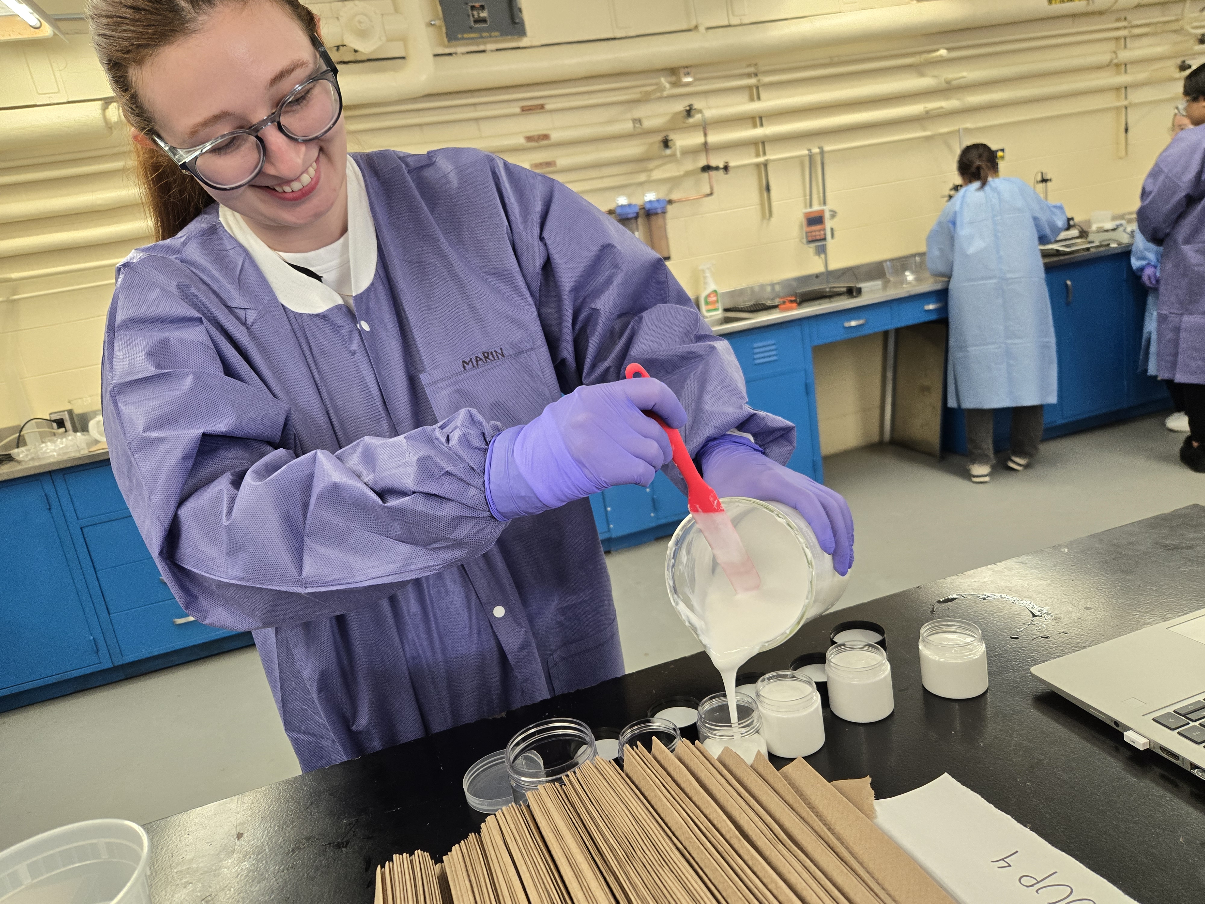 A student pouring white solution in a jar in the laboratory