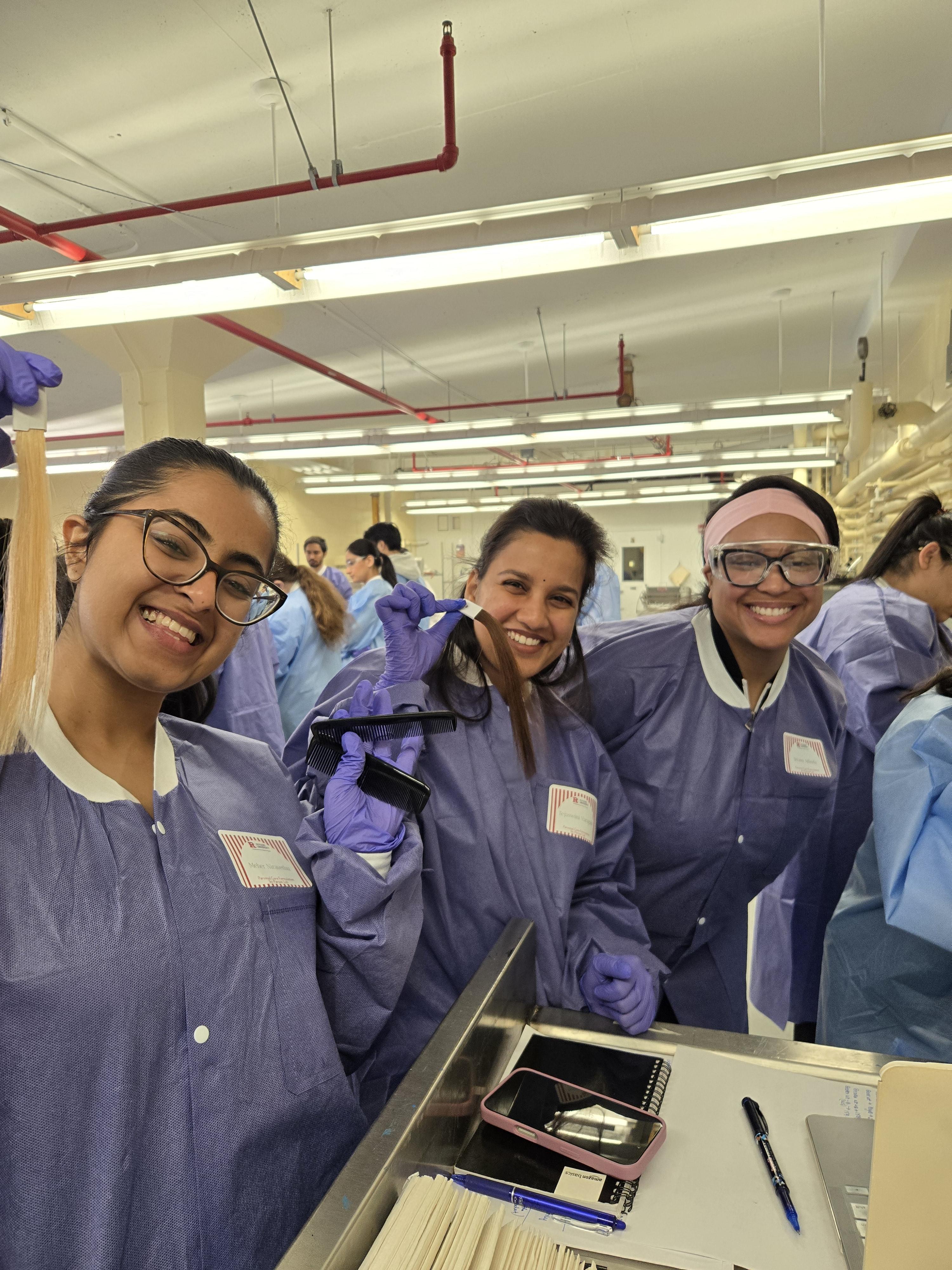 A group of students posing and smiling while holding hair extensions and combs