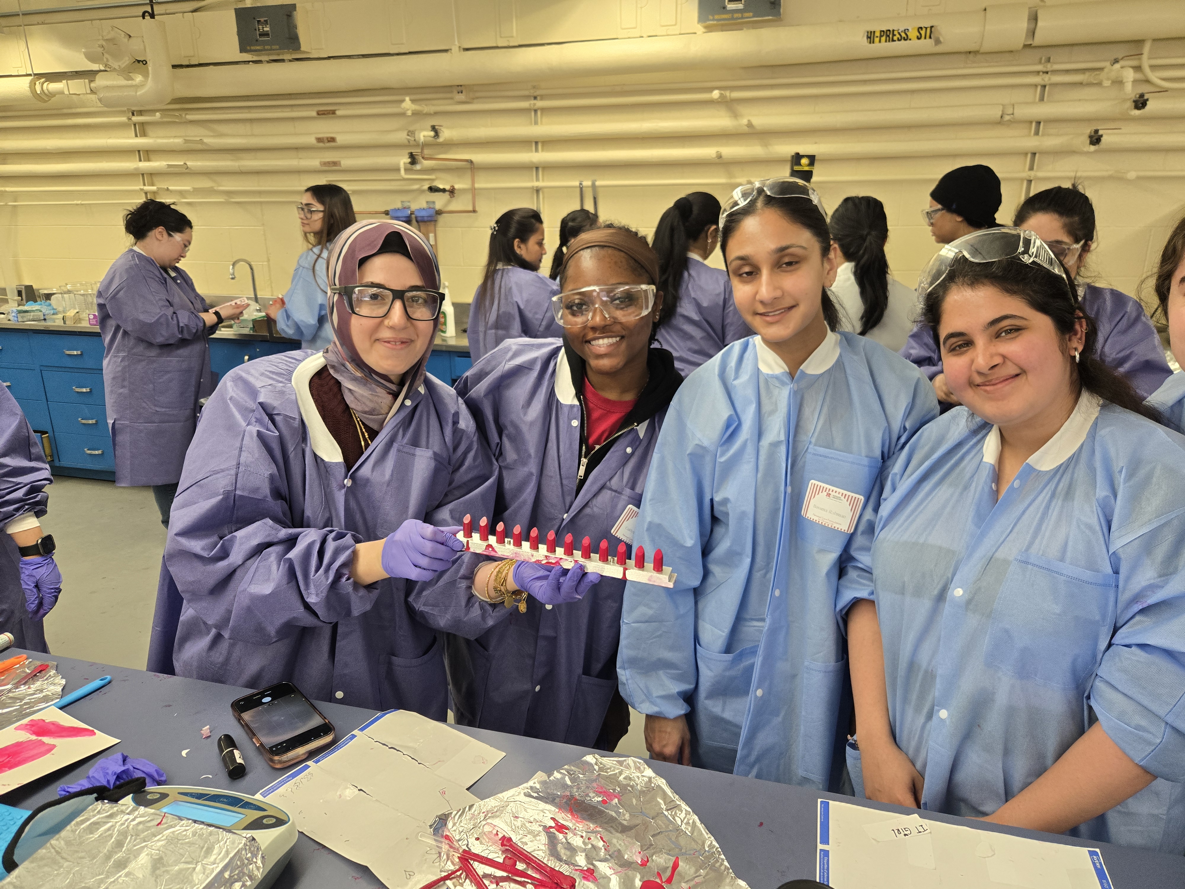 A group of 4 students holding the formulated lipsticks in lab