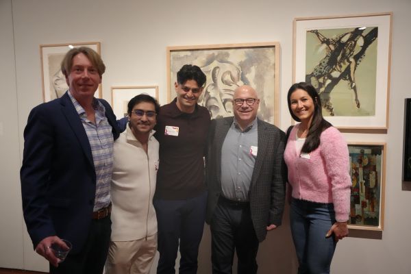 5 people posing together for a photo with a backdrop of artistic paintings