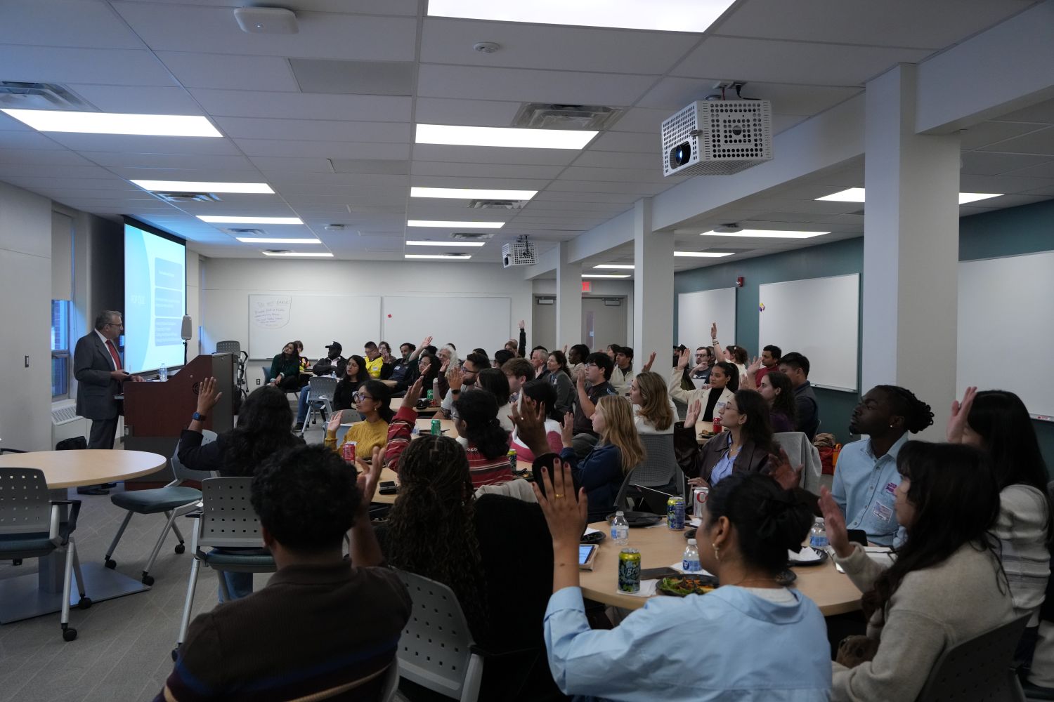 Students in a class raising their hands to answer