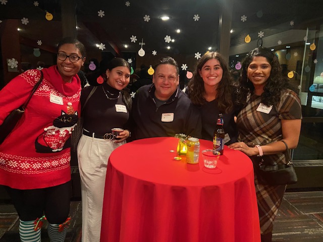 group standing around red table, smiling