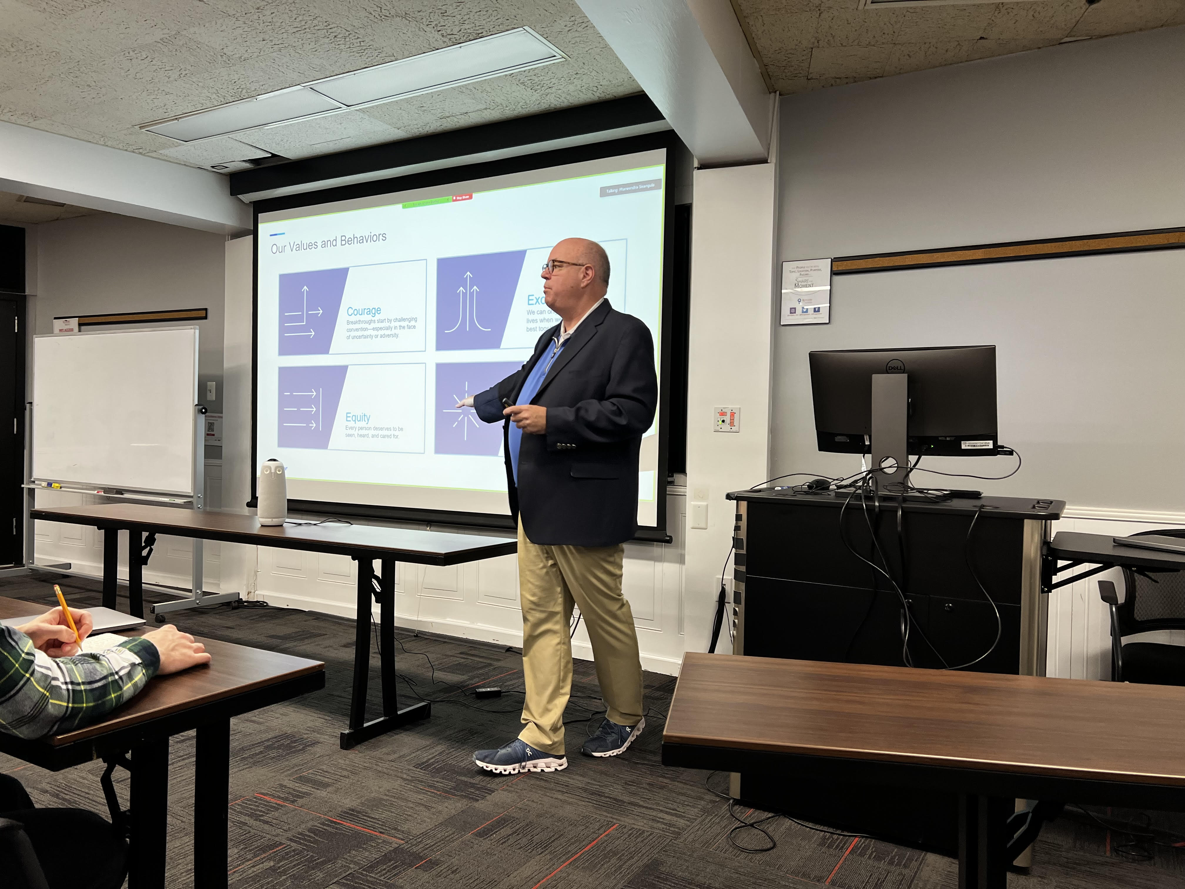 Speaker presenting to class in front of screen