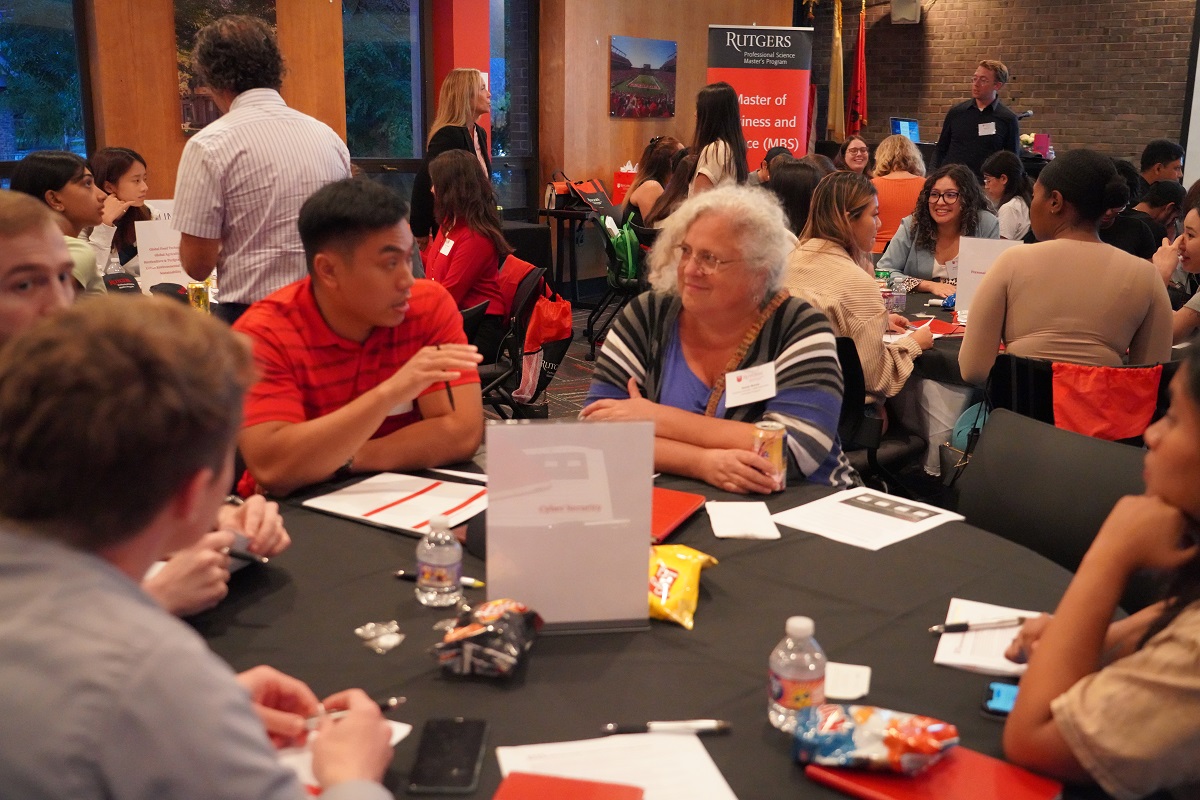 students and faculty member sitting at a table, talking.