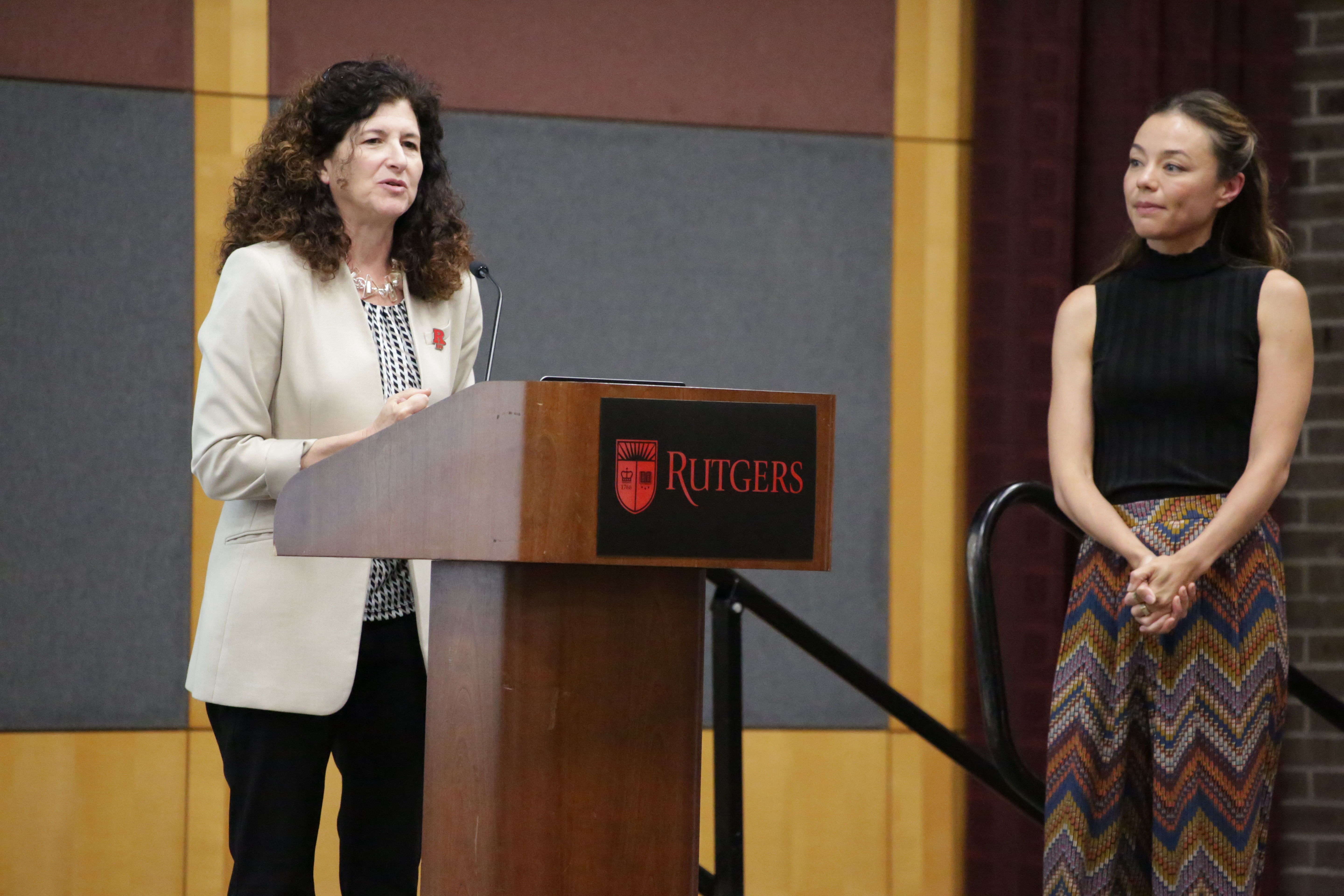 woman standing at podium introducing woman off to side