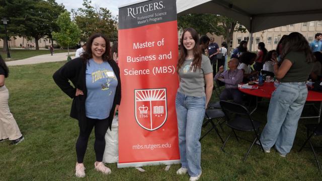 Two students posing with the event banner