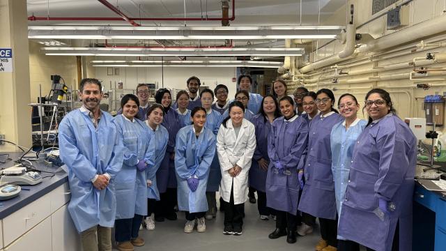 A group of students wearing labcoats and posing in a laboratory