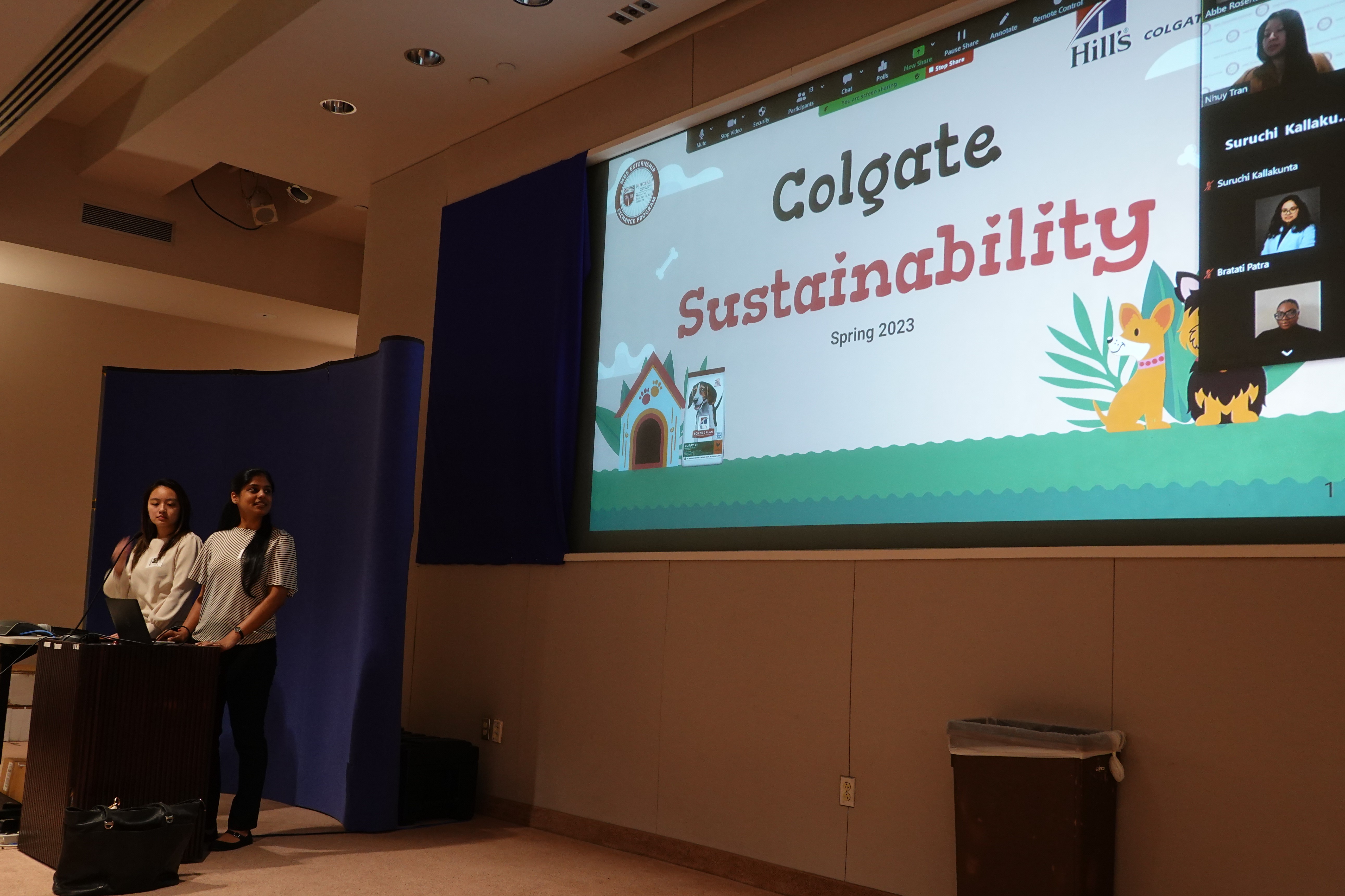 Students standing at podium in front of opening slide