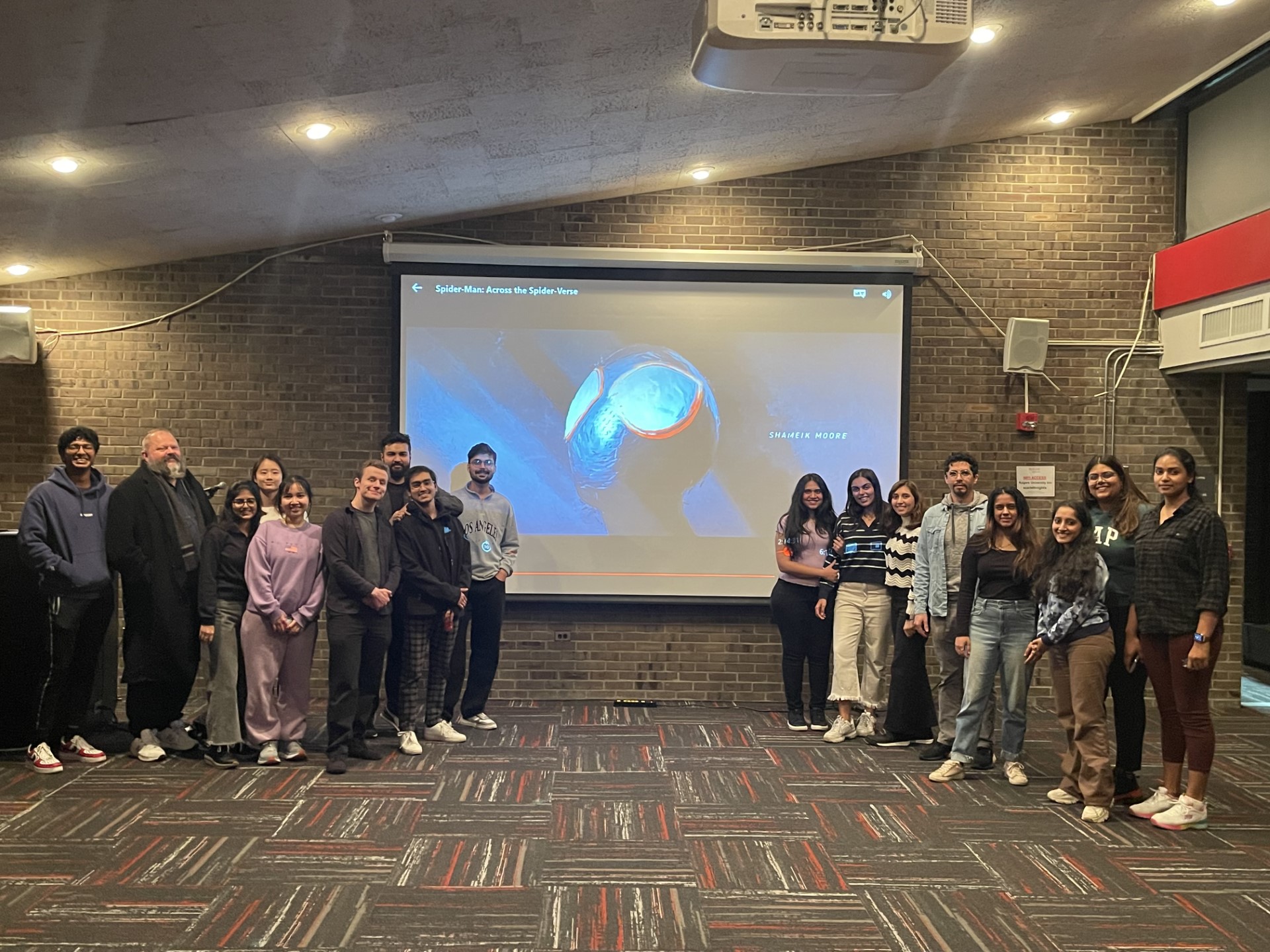 Group of students standing in front of projection screen with movie playing
