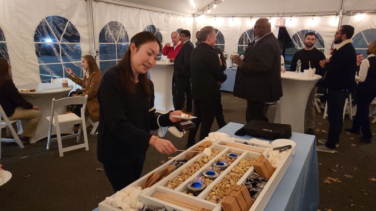 student in front of DIY s'mores station / table display of marshmallows, chocolate squares, graham crackers, and sterno lights