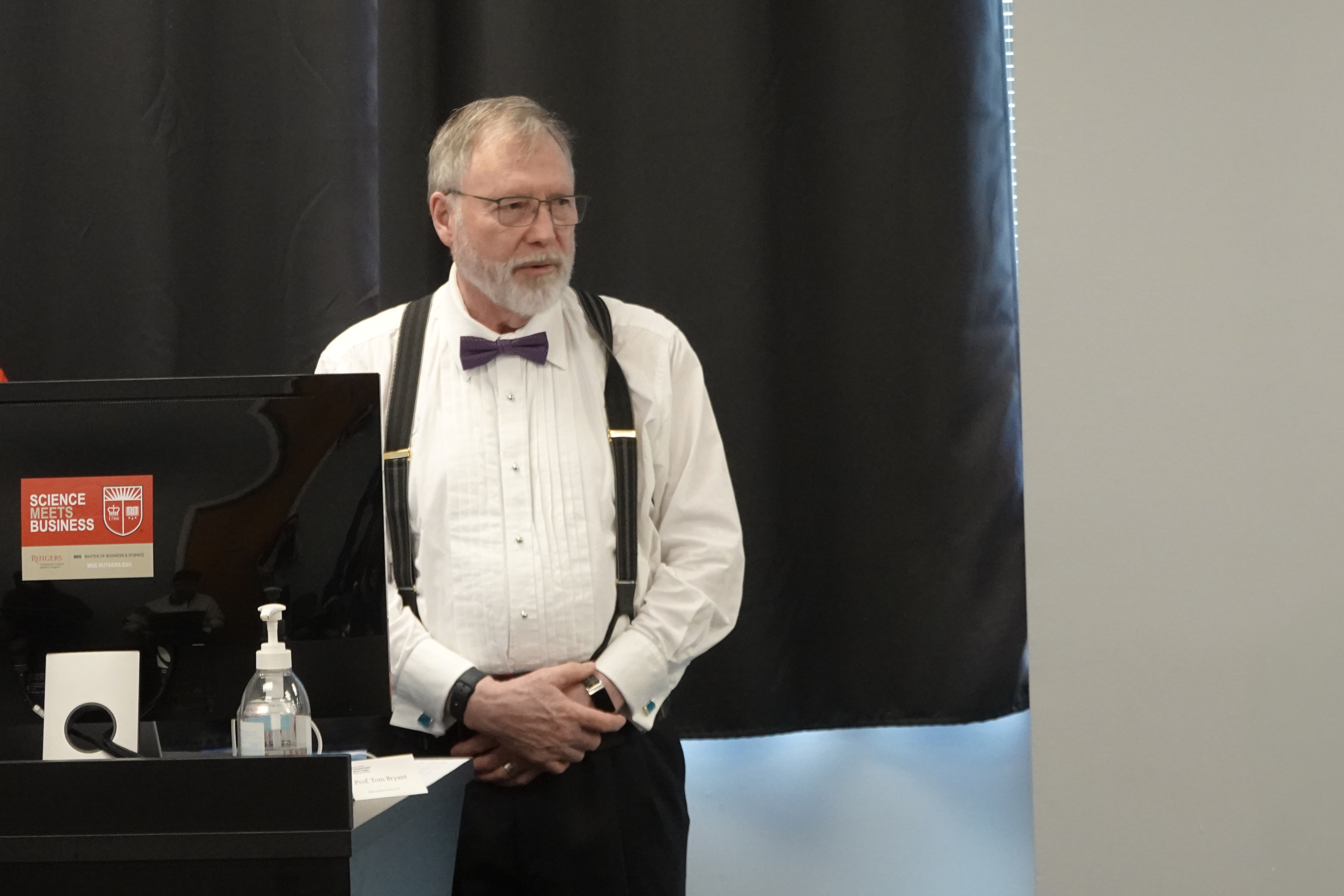 Man standing at podium next to "Science Meets Business" sticker