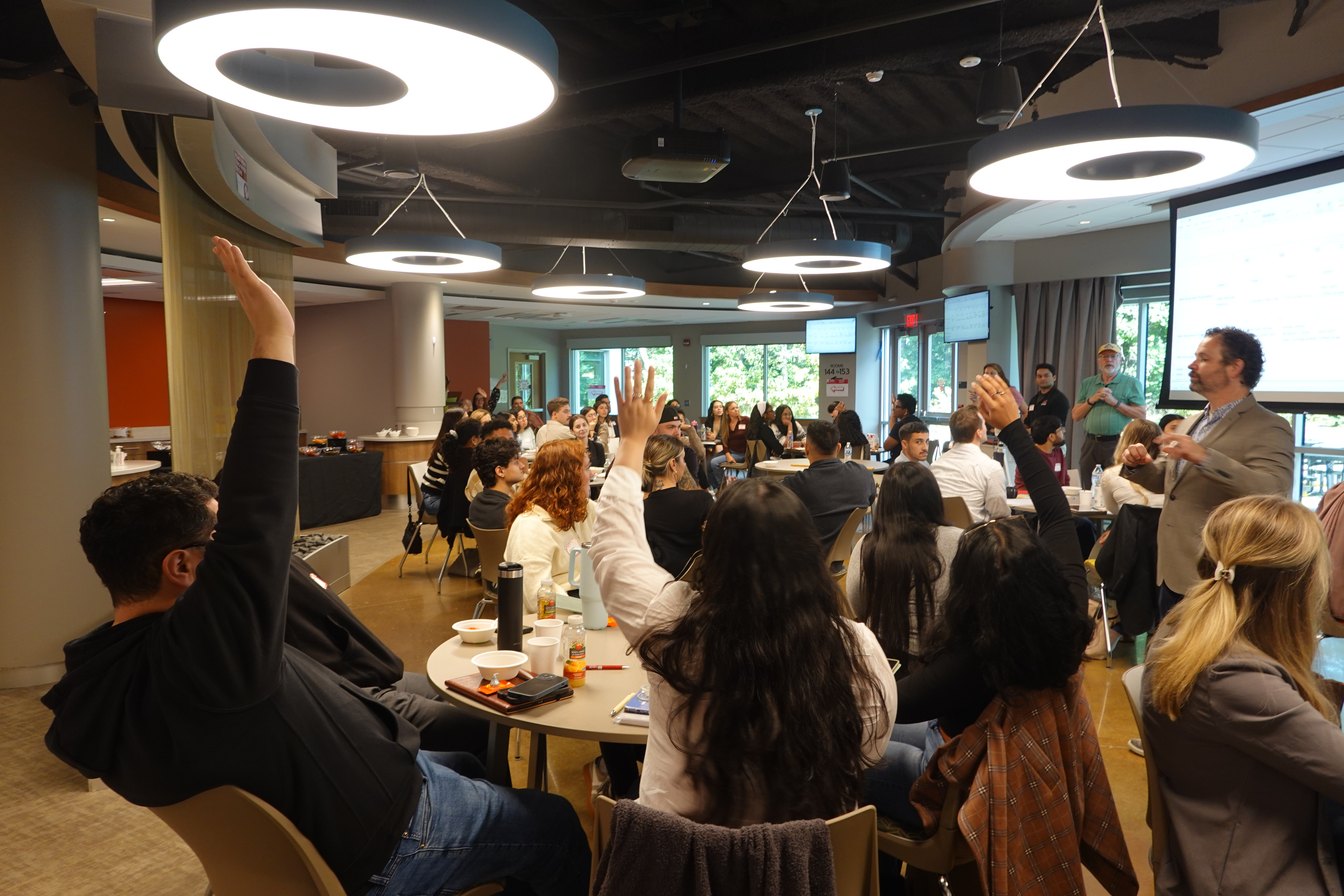 Bunch of people in a conference raising hands to answer a question