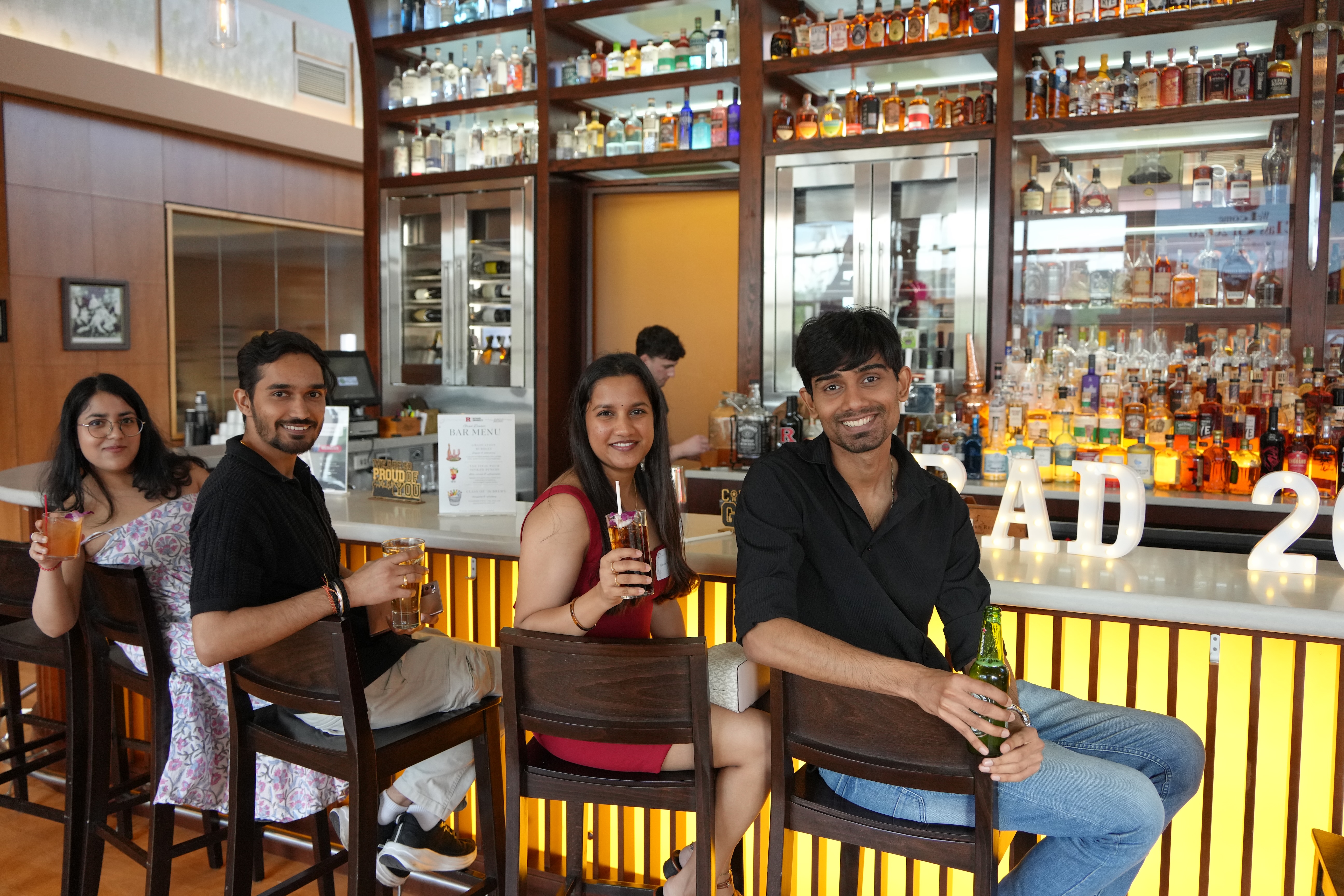 four people sitting at a bar