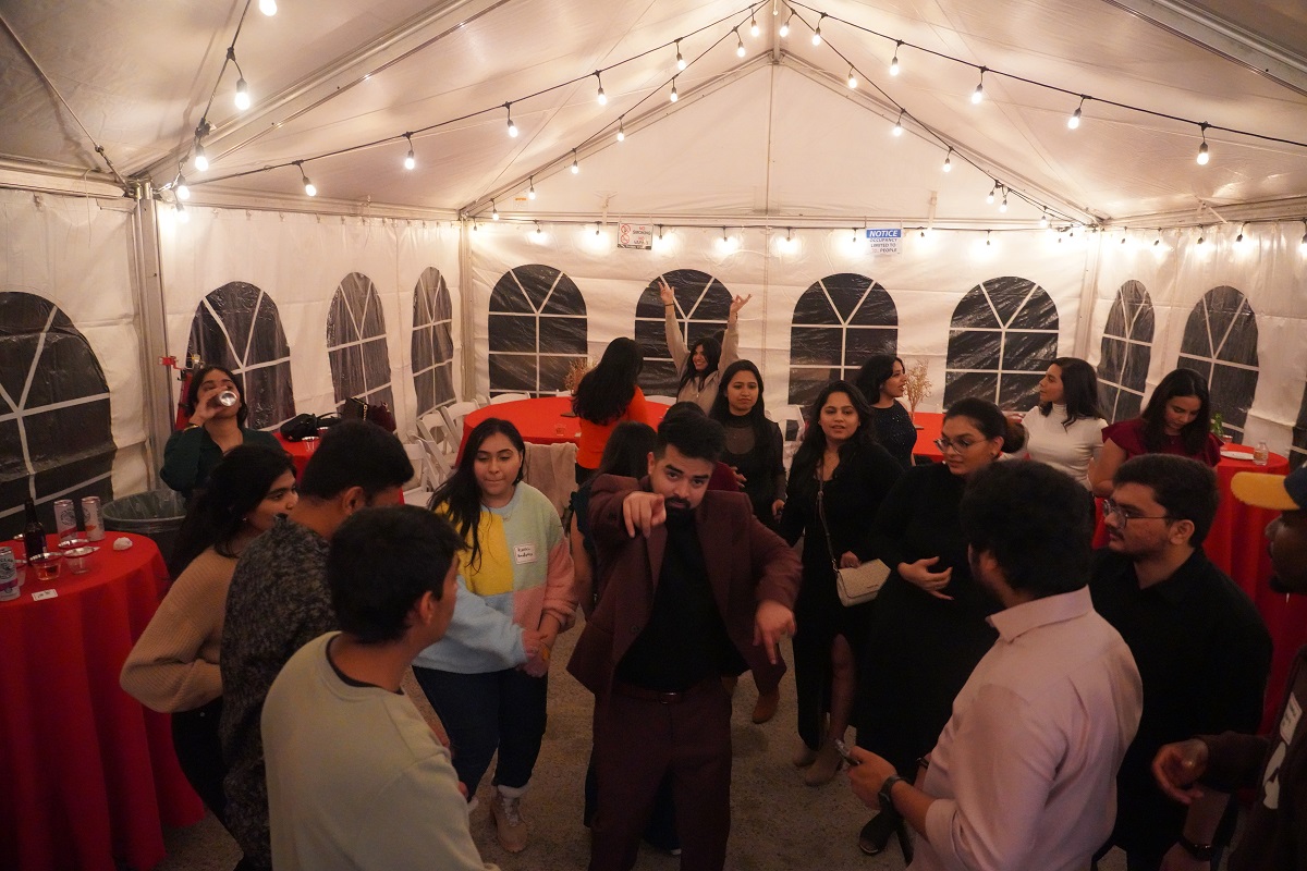 candid photo of people dancing in a white tent with lights