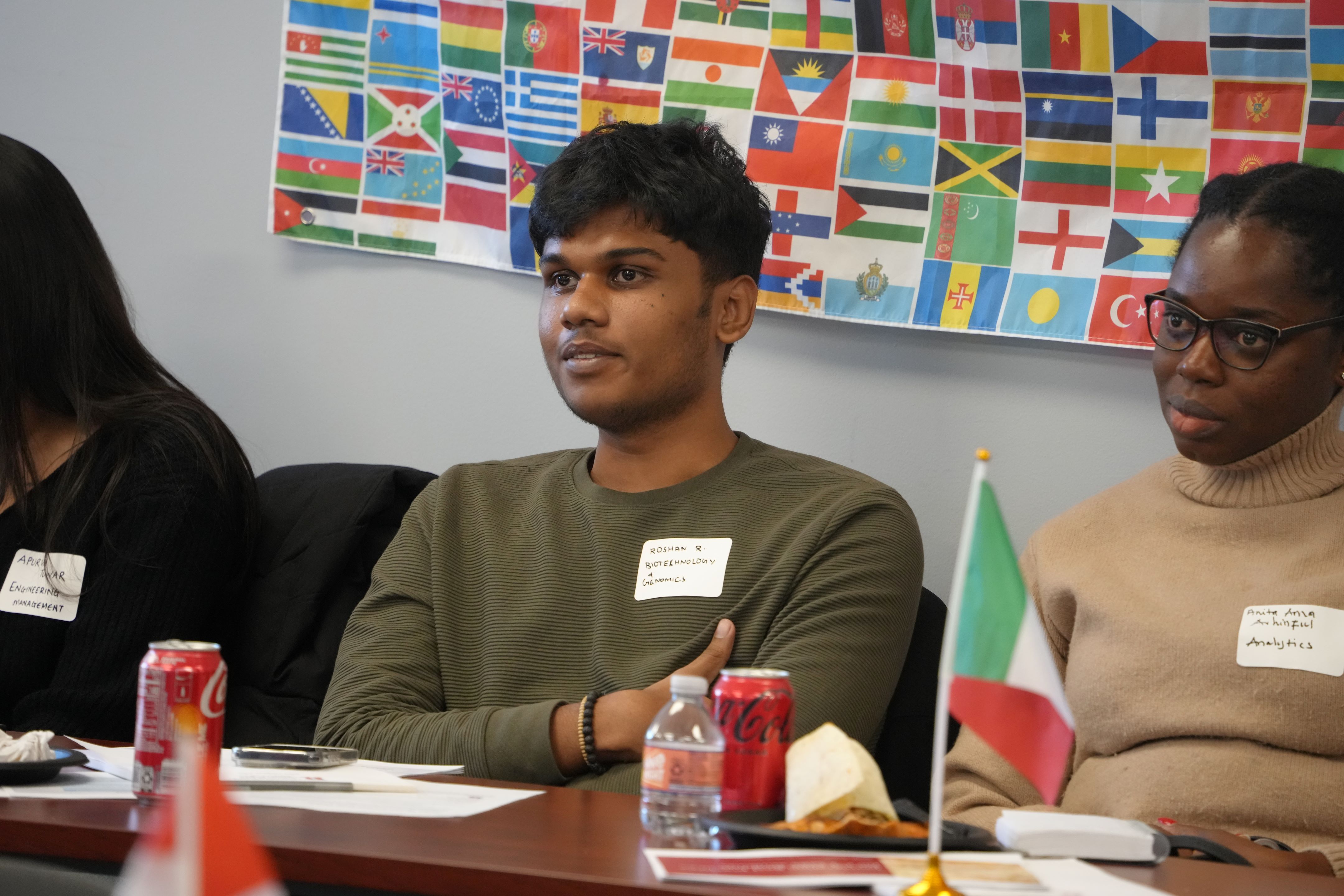 students sitting at table with flags in background