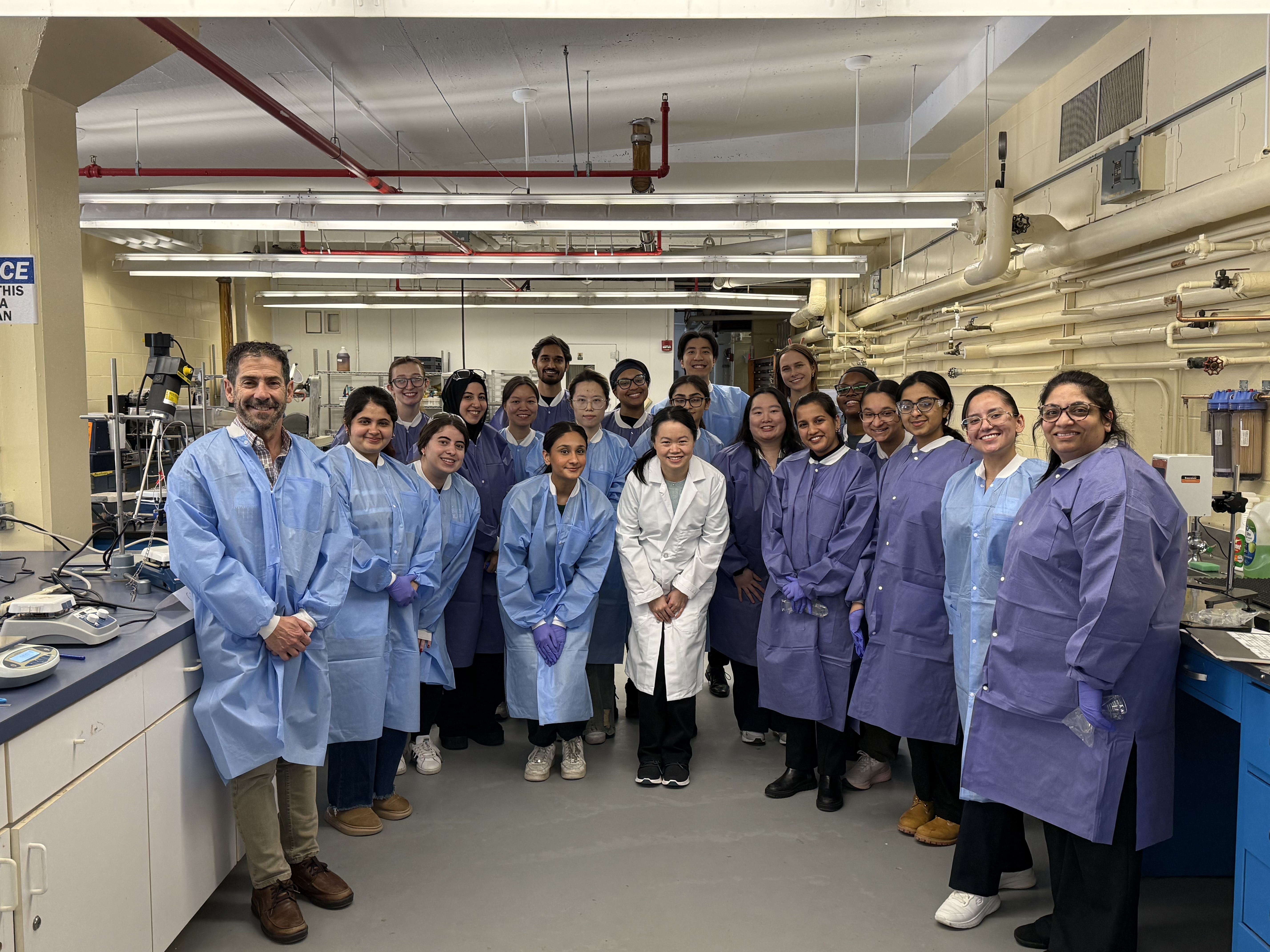 A group of students wearing labcoats and posing in a laboratory