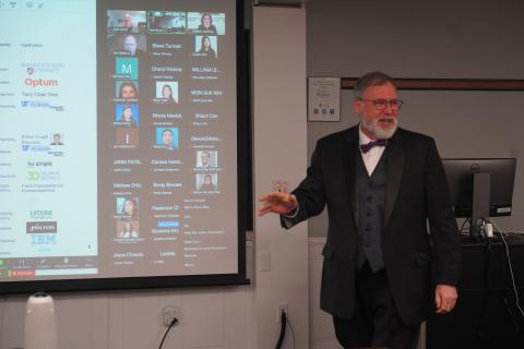 Man dressed formally in front of projector screen